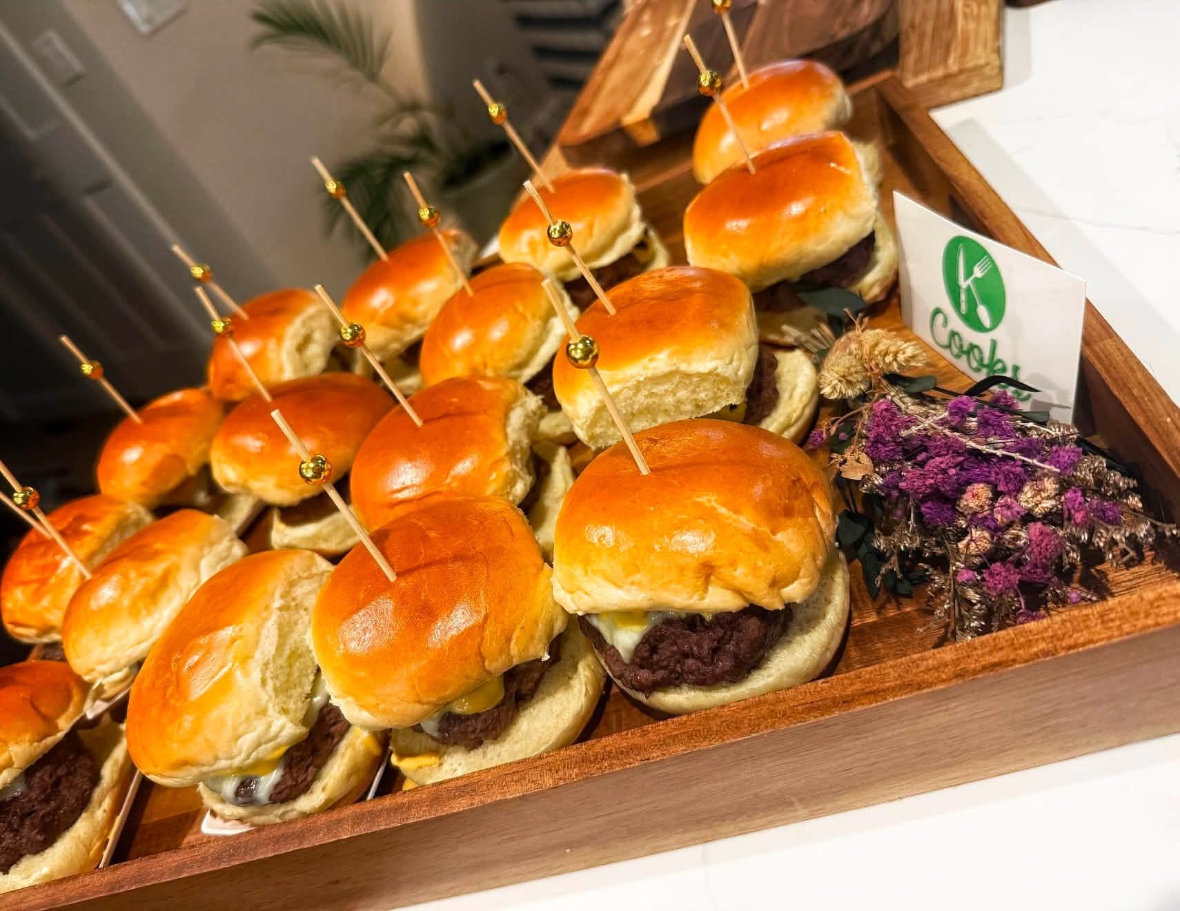 K Cooks cheeseburger sliders with skewers on a wooden serving board