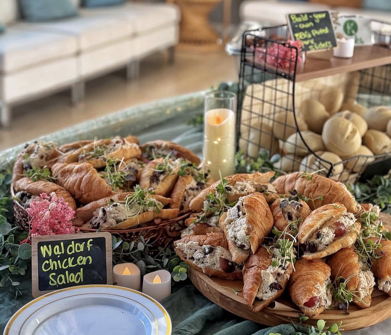 Waldorf chicken salad croissants on a styled display with candles and dinner rolls