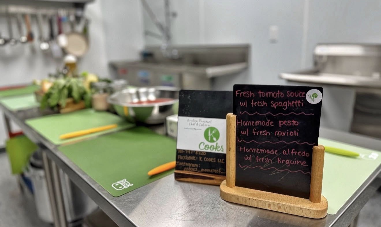 K Cooks cooking class setup with green cutting boards and a chalkboard menu of fresh pasta dishes