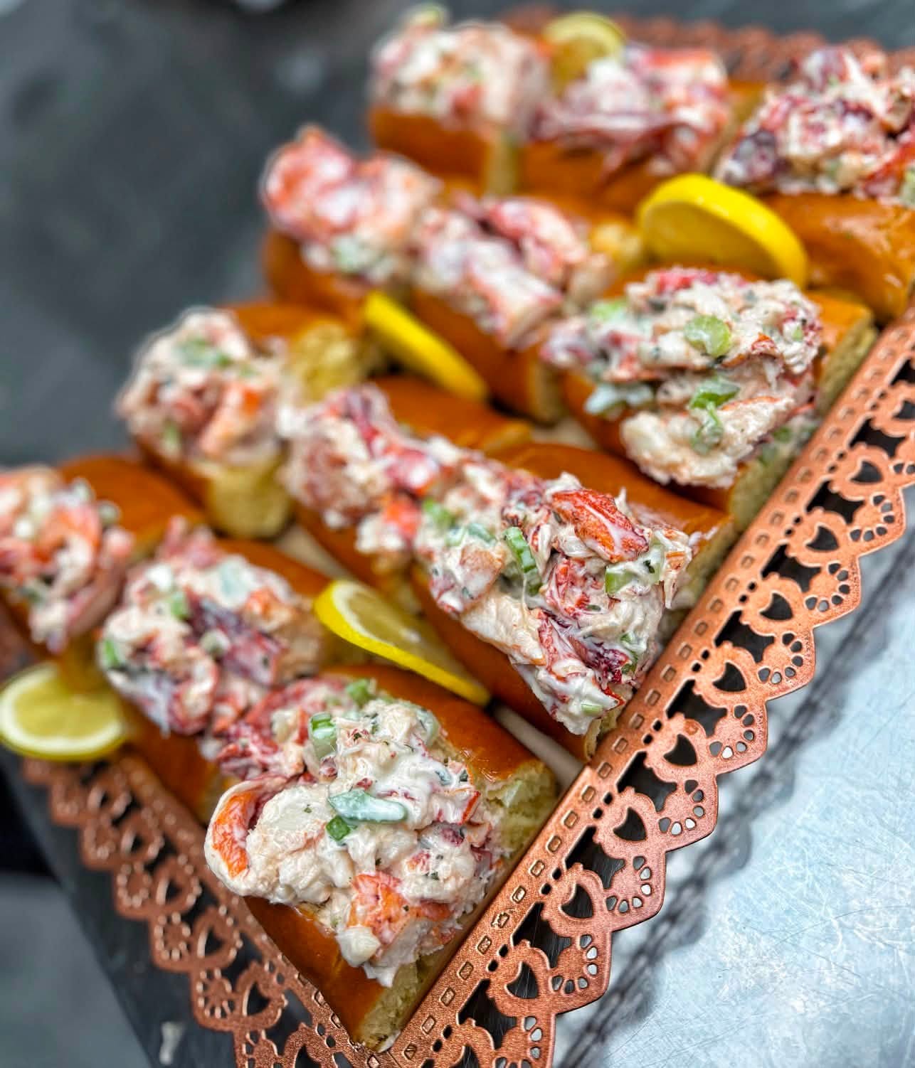 Mini lobster rolls with lemon on a copper tray