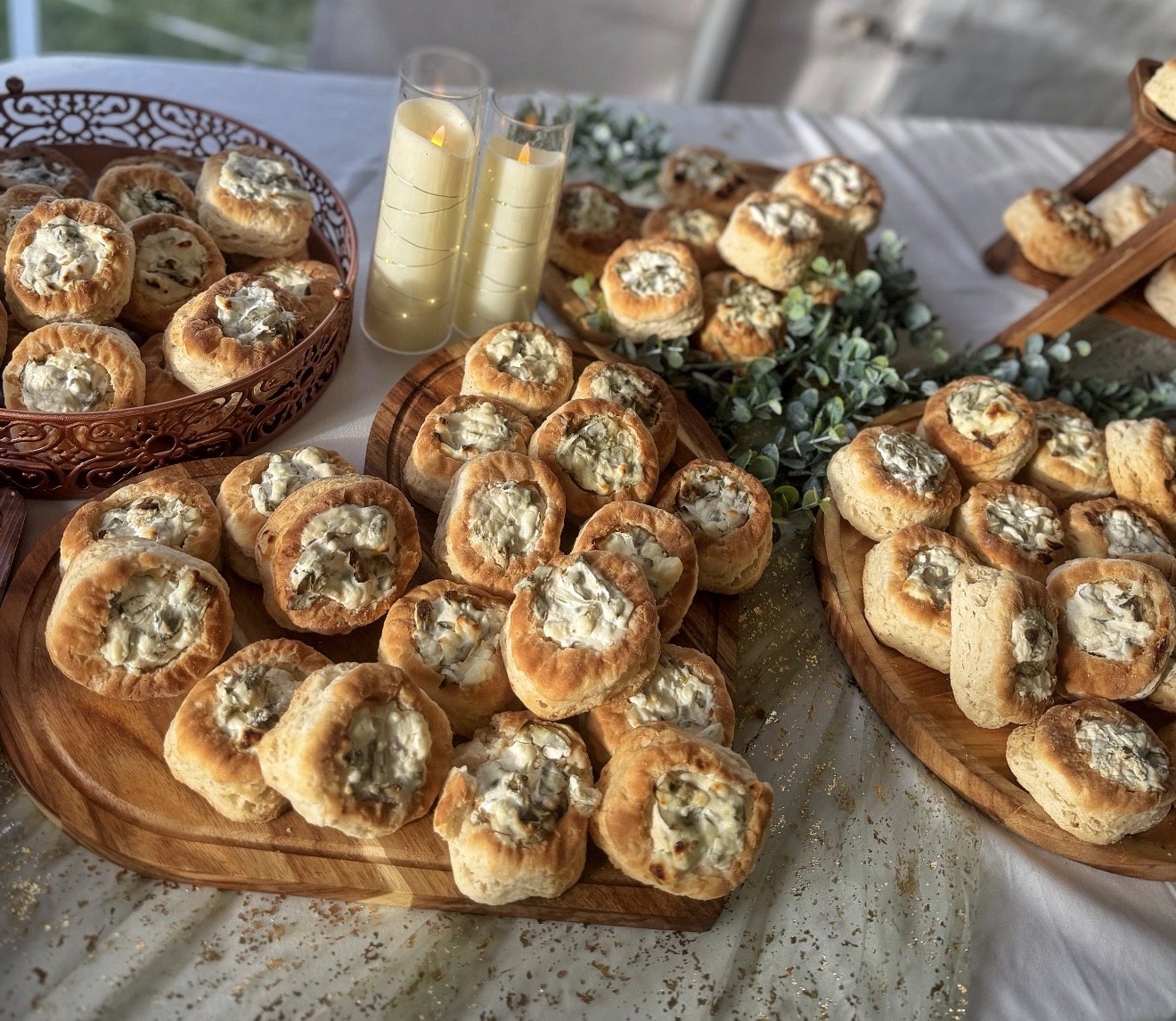 Wooden boards of stuffed bread bites on a display with eucalyptus greenery