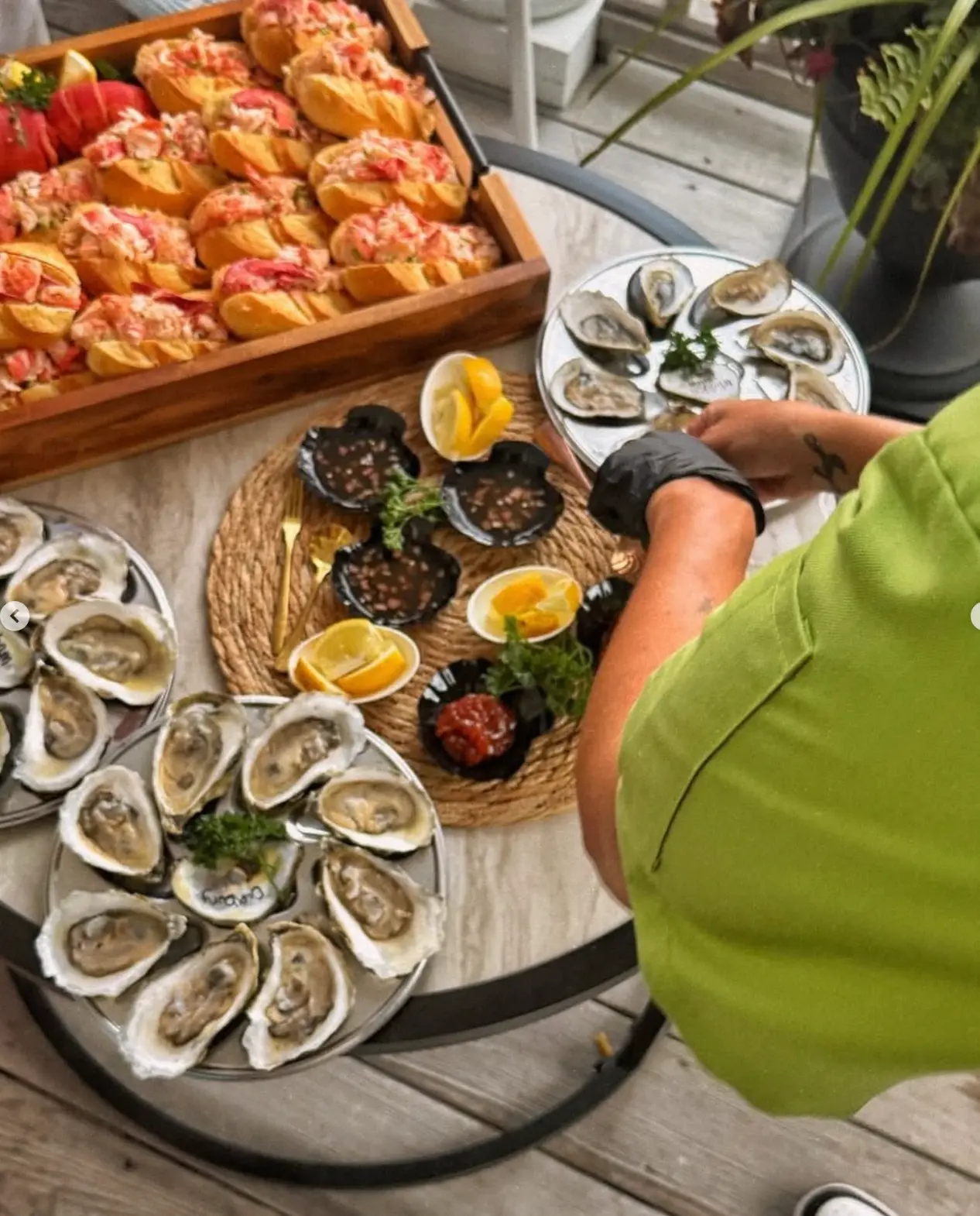 Chef Kristen preparing oysters beside a tray of lobster rolls